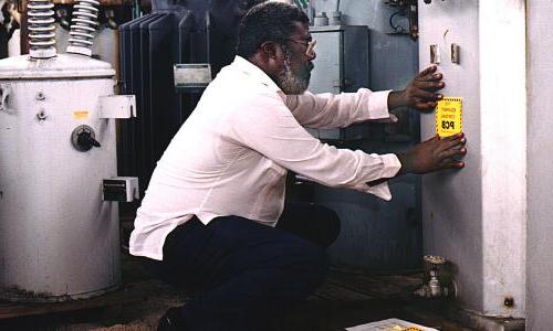 A person kneeling down and labeling equipment that contains PCBs.